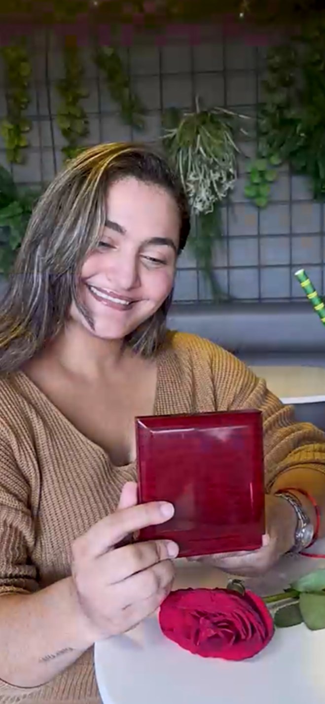 Woman laughing with joy while unboxing a JeweLayer necklace gift