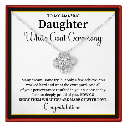 A silver necklace with a heart-shaped pendant set with small clear stones, presented on a white card with a red frame. The card reads 'TO MY AMAZING Daughter White Coat Ceremony' with a congratulatory message.