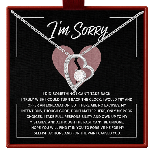 A silver necklace with a broken-heart pendant and clear center stone, presented on a black card inside a red gift box. The card reads 'I'm Sorry' with a pink heart graphic and a long apology message below.