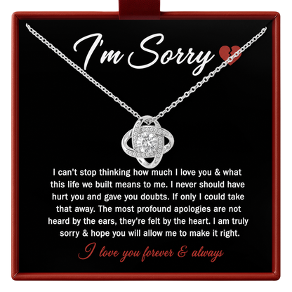 A silver apology necklace with a heart-shaped pendant is displayed on a black gift card inside a red box. The card features the words 'I'm Sorry' and a small red heart, along with a long message of apology and the phrase 'I love you forever & always' in red script.