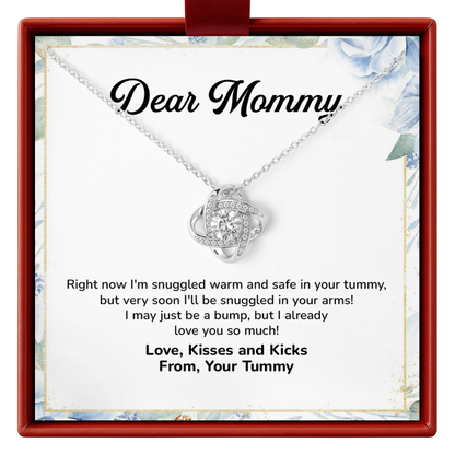 A silver necklace with a heart-shaped pendant set with small clear stones, presented on a white card inside a red gift box. The card is addressed 'Dear Mommy' and features a humorous baby quote.