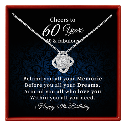 A silver necklace with a heart-shaped pendant is displayed inside a red gift box. The necklace is presented on a black background with blue damask pattern, featuring a message for a 60th birthday.