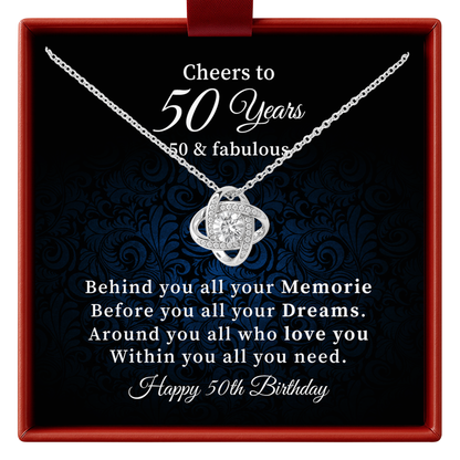 A silver 50th birthday necklace with a heart-shaped pendant is presented inside a red gift box with a black printed insert. The insert features celebratory text reading 'Cheers to 50 Years 50 & fabulous' and a sentimental message for a 50th birthday.