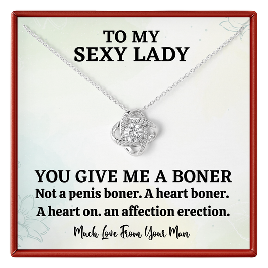Necklace with heart pendant on a card with humorous text, displayed in a red border.