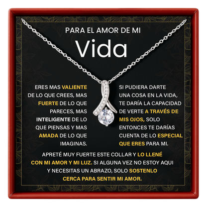 Silver necklace with a diamond pendant on a black card with text, framed by a red border.