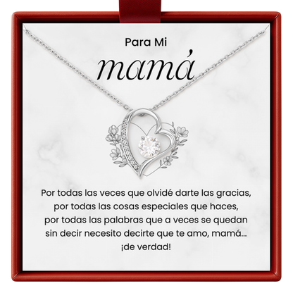 Heart-shaped necklace with floral details on a white card with red border, featuring Spanish text.