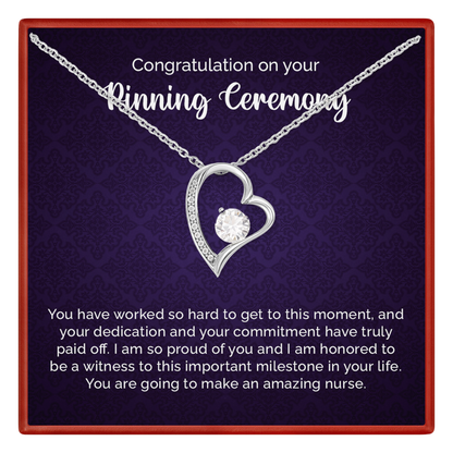 Heart-shaped necklace with a message card for a pinning ceremony on a dark background