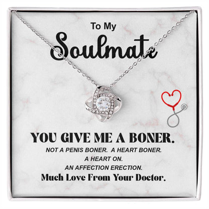 A humorous gift necklace with a heart-shaped pendant, presented in a box that reads 'To My Soulmate' and a message related to a medical theme. The necklace is accompanied by a small heart and stethoscope icon.